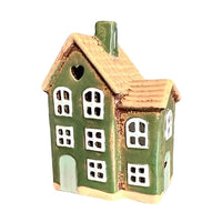 Grönt keramikhus med vita fönster sett snett från sidan