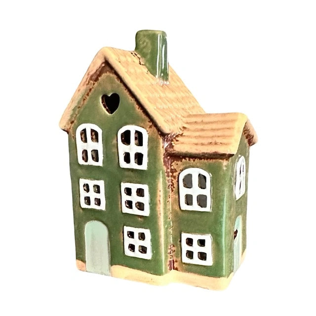 Grönt keramikhus med vita fönster sett snett från sidan