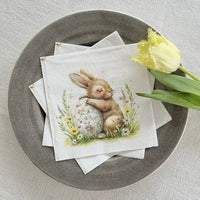 Servett med kanin och påskägg upplagda i fat