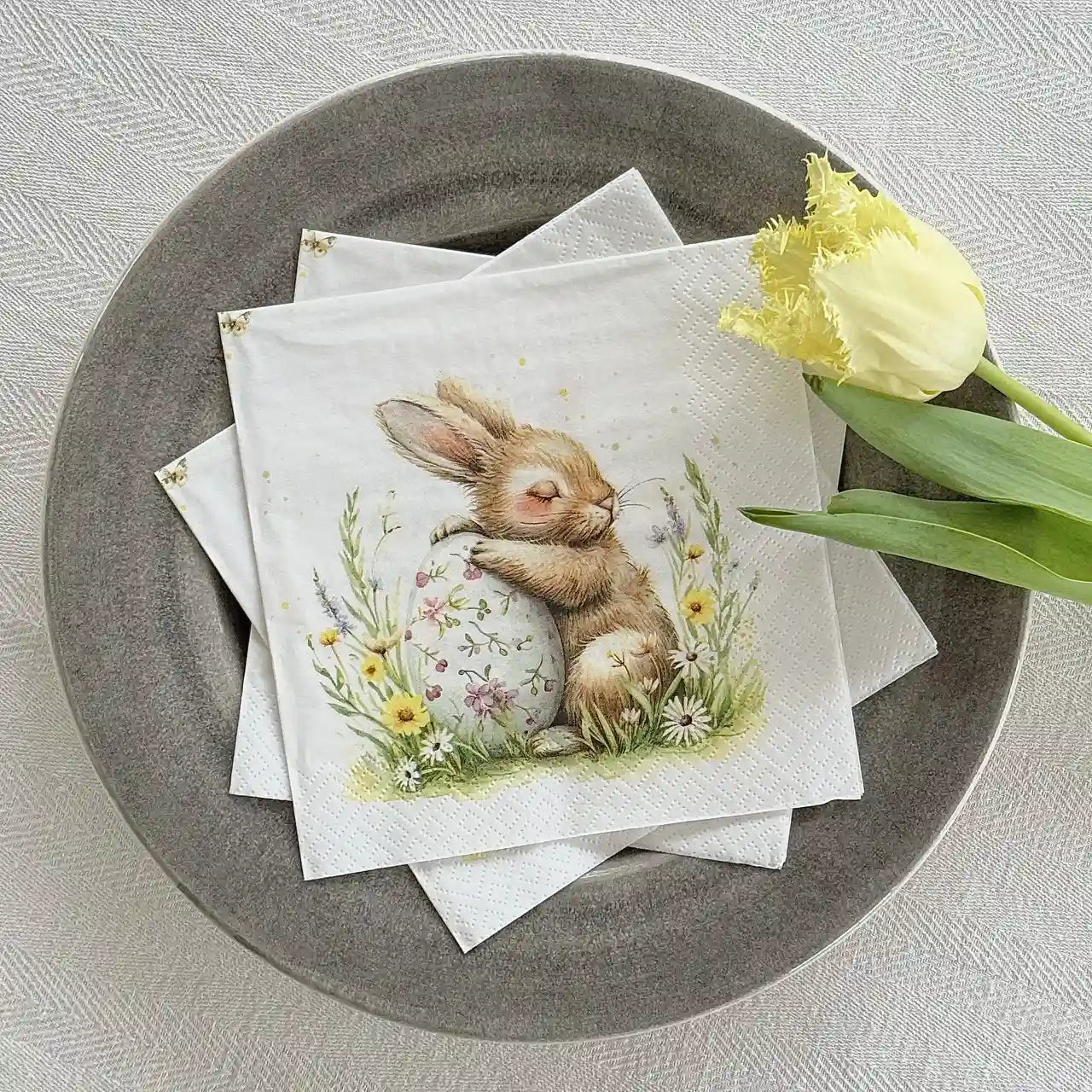Servett med kanin och påskägg upplagda i fat